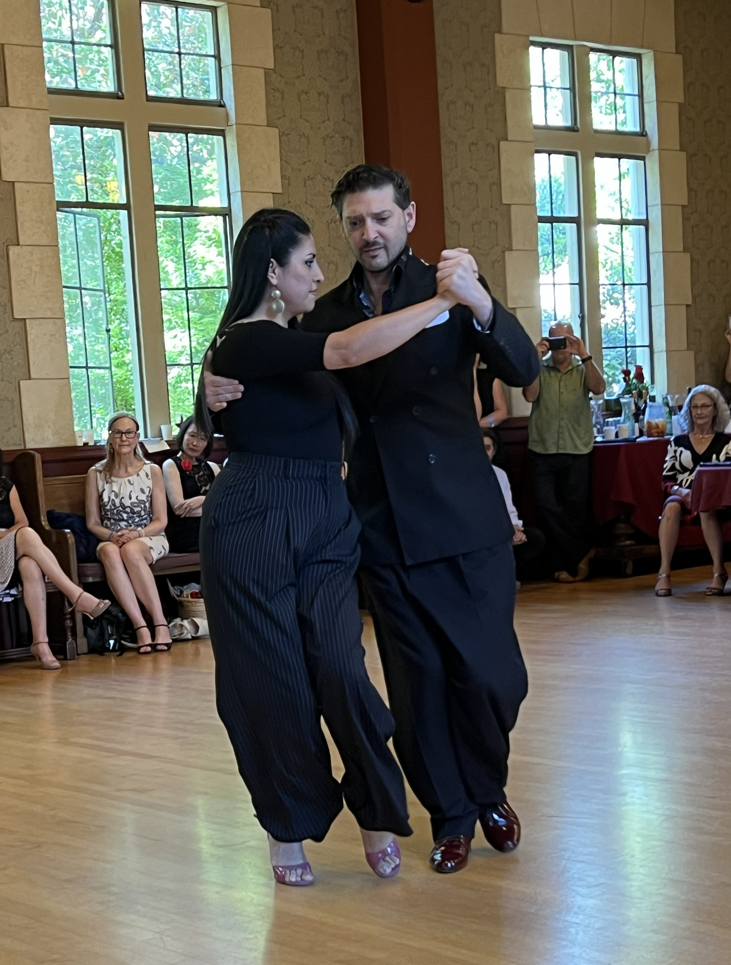 Tango dancers in close embrace on the polished wooden floor at Empanada Milonga.