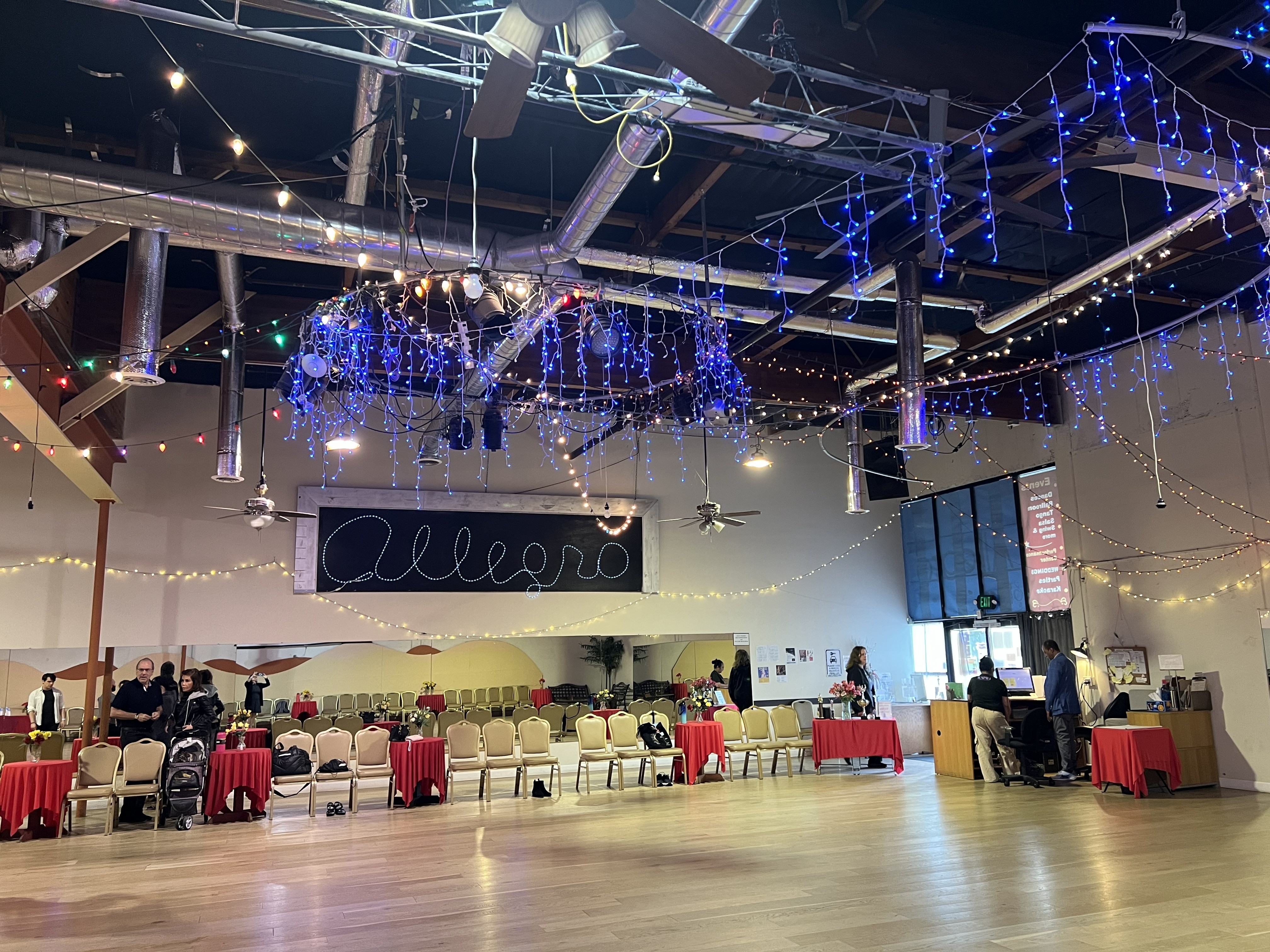 Main ballroom at Allegro Ballroom with string lights, chairs, and open wooden dance floor.