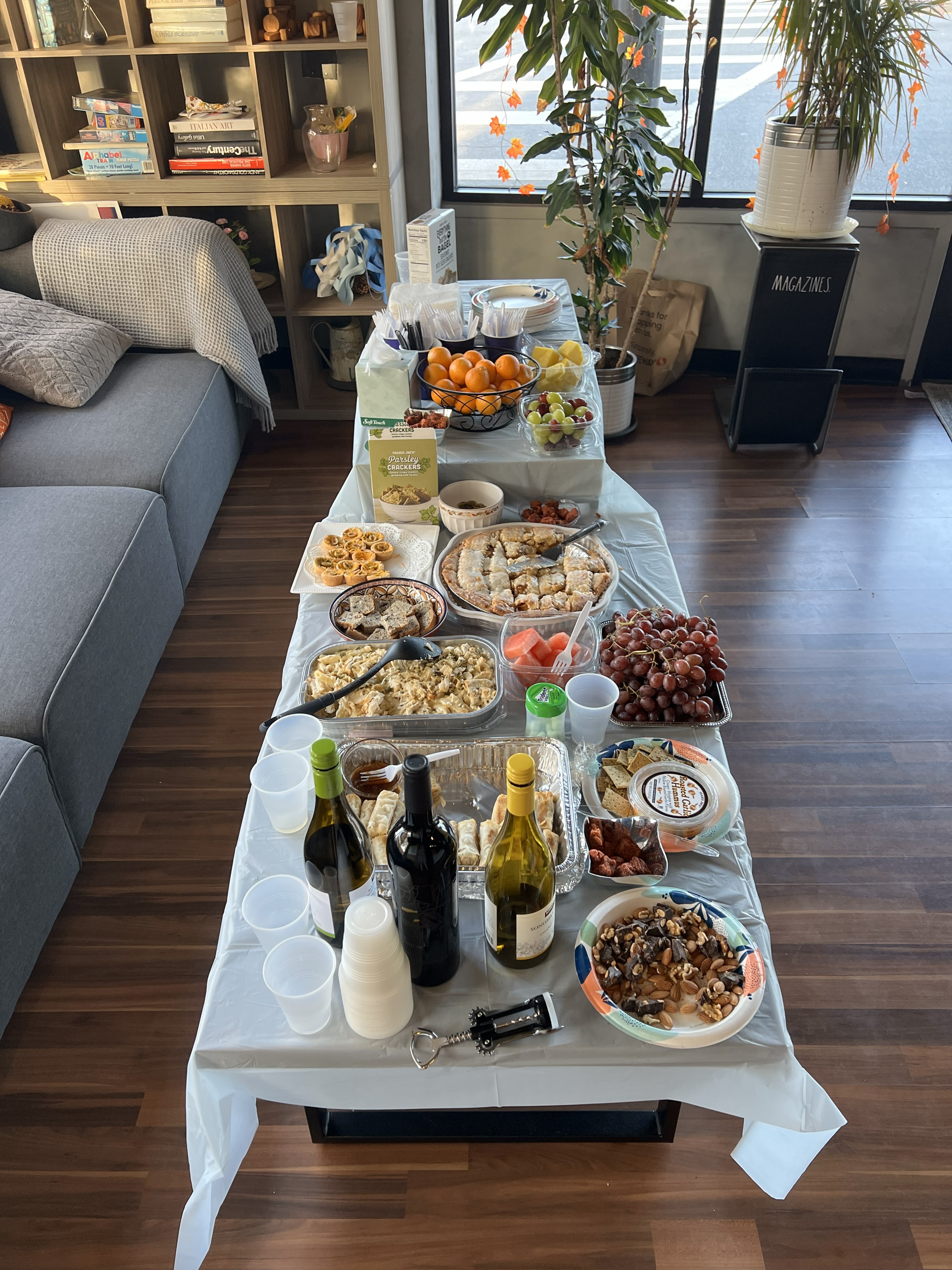 Thanksgiving-style potluck table at Afternoon Practilonga with La Cadencia Tango, covered with snacks, hot dishes, fruit, wine, and desserts.