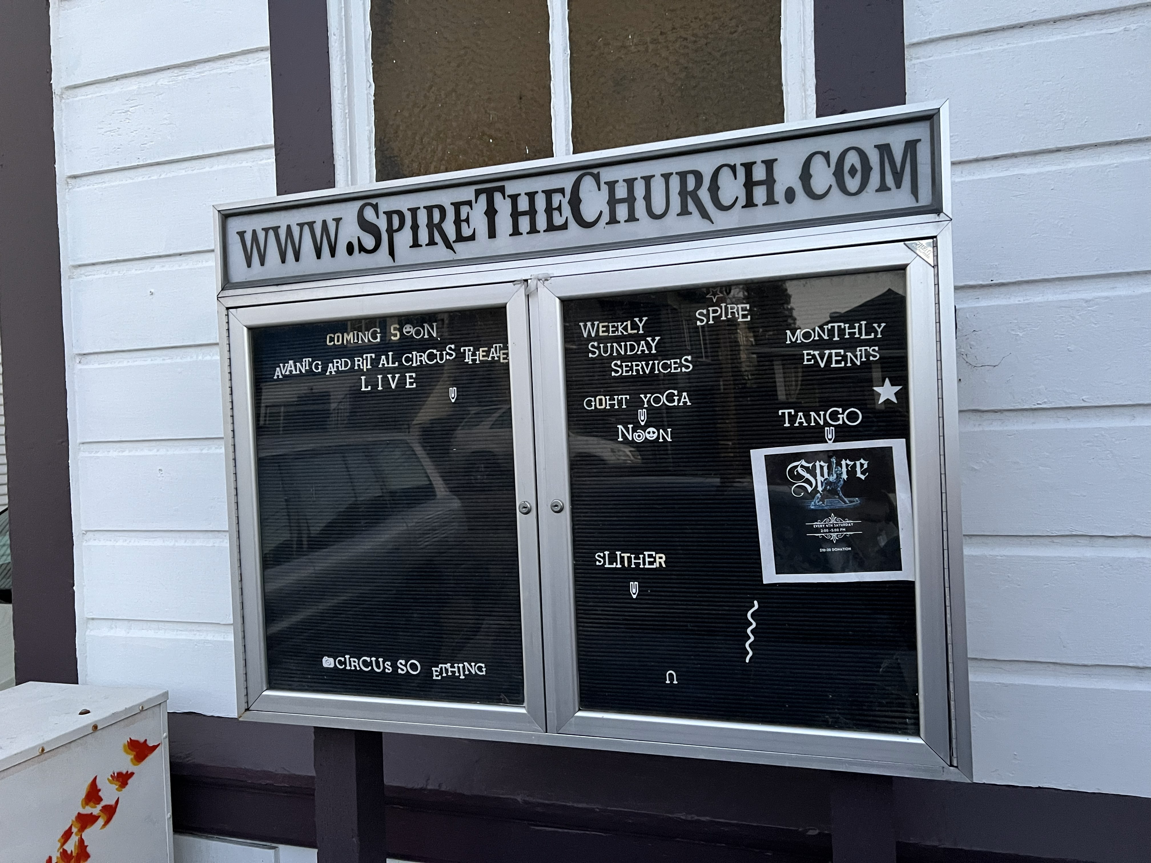 Interior of Spire hall with wooden floor, balcony, chandelier lights, and seating area.